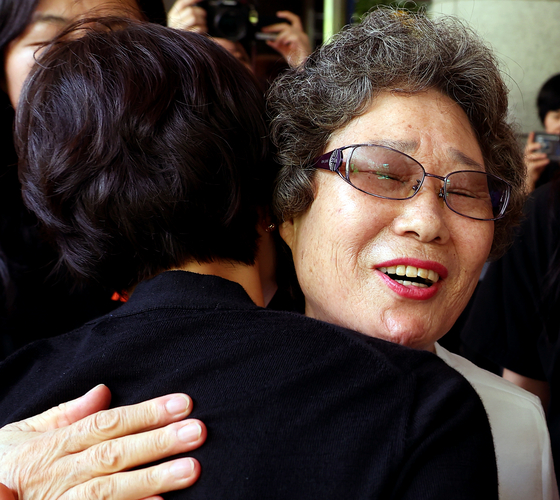 法廷を出て弁護人と抱擁するチェ・マルジャさん［写真　聯合ニュース］