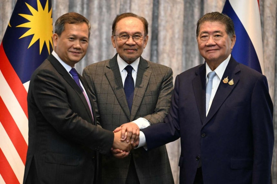 ２８日、マレーシアのイブラヒム首相（中央）、カンボジアのフン・マネット首相（左）、タイのプームタム・ウェーチャヤチャイ（右）が同日、マレーシアのプトラジャヤで、タイとカンボジア間の停戦の可能性についての会談後、記者会見を終え、握手をしながら写真を撮影している。［写真　聯合ニュース］