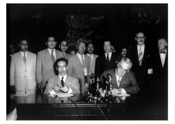１９５３年８月８日、景武台〔ヒョンムデ、青瓦台（チョンワデ、大統領府）の前身〕で開かれた韓米相互防衛条約の仮調印式。卞栄泰（ピョン・ヨンテ）外務長官とダレス国務長官の背後で、李承晩（イ・スンマン）大統領が調印式を見守っている。［中央フォト］