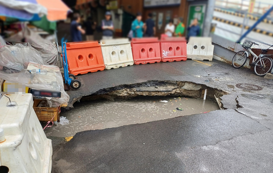 １２日午前、釜山市沙上区のセビョク市場近くの道路に縦５メートル、横１メートルの大規模な道路陥没が発生し接近が規制されている。陥没が発生した地点は釜山都市鉄道沙上下端線の工事現場近くだ。［写真　聯合ニュース］