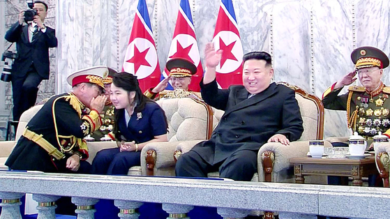 ２０２３年９月８日、平壌の金日成広場で開かれた北朝鮮政権樹立７５周年民防衛武力軍事パレードで北朝鮮の金正恩国務委員長と並んで座った金ジュエ氏に朴正天党軍政指導部長がひざまずいて耳打ちしている。［写真　聯合ニュース］