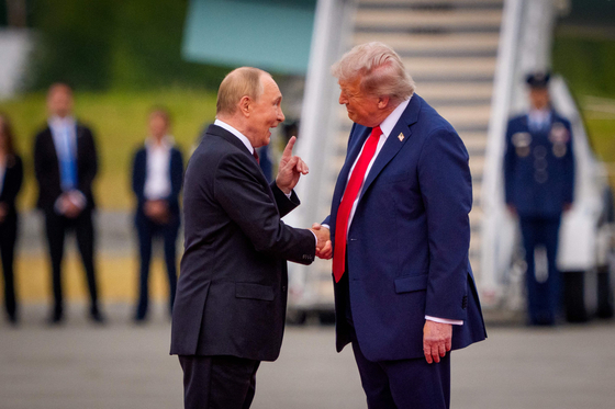 １５日（現地時間）、プーチン大統領（左）が米アラスカ州エルメンドルフ・ リチャードソン統合基地に到着した後、トランプ大統領と握手しながら人差し指を立てている。［ＡＦＰ＝聯合ニュース］