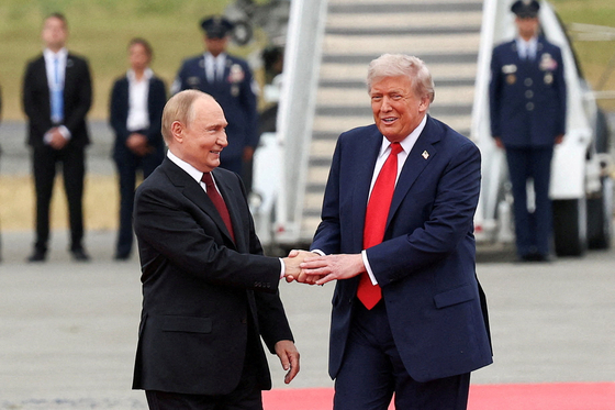  プーチン大統領（左）とトランプ大統領が握手している。［ロイター＝聯合ニュース］