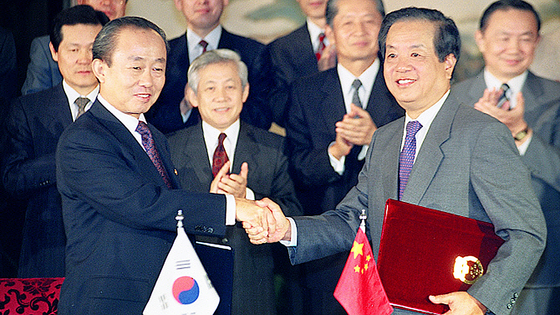 １９９２年８月２４日、韓国の李相玉（イ・サンオク）外務長官（左）と中国の銭其琛外交部長（右）が中国北京の釣魚台国賓館で「韓中外交関係樹立に関する共同声明書」を交換した後、握手を交わしている。［写真　聯合ニュース］