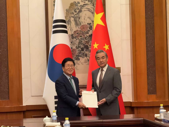 ８月２４日、中国北京の釣魚台国賓館１２号楼で、朴炳錫（パク・ビョンソク）（左）大統領特使が王毅（右）中国外交部長に李在明（イ・ジェミョン）大統領の親書を手渡している。［写真　北京特派員団共同取材］