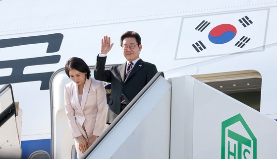 韓国の李在明（イ・ジェミョン）大統領と金恵景（キム・ヘギョン）夫人が１泊２日の訪日日程を終えて２４日午後、東京羽田空港から米国ワシントンに向かう大統領専用機「空軍１号機」に搭乗しながら挨拶をしている。［写真　大統領室写真記者団］