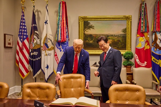 トランプ米国大統領が２５日にホワイトハウスで開かれた韓米首脳会談に先立ち李在明大統領が芳名録を作成できるようにいすを引いている。キム・ヒョンドン記者