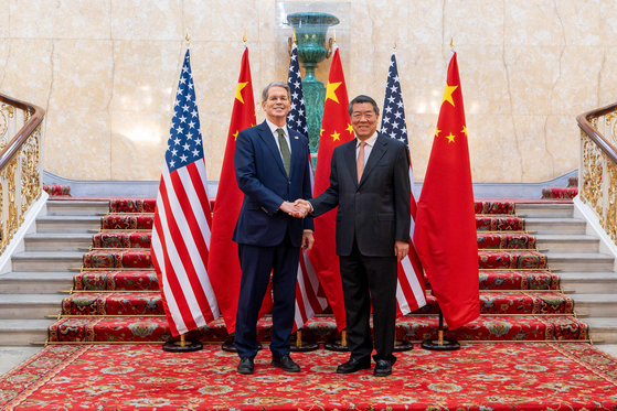 米中貿易交渉を率いるベッセント米財務長官（左）と何立峰中国副首相が6月9日に英ロンドンで会い握手をしている。［写真 AFP＝聯合ニュース］