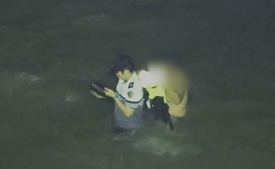 韓国海洋警察の故イ・ジェソク警長が11日、仁川霊興島（インチョン・ヨンフンド）の干潟で孤立した中国人70代男性に救命胴衣を脱いで渡している様子。［写真 仁川海洋警察署］