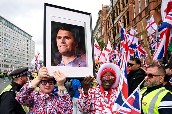 13日にロンドンで開かれた反移民集会で参加者がチャーリー・カークの写真を手にしている。［写真 ロイター＝聯合ニュース］