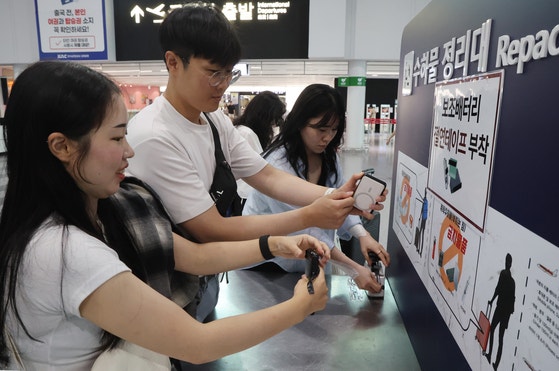 釜山（プサン）金海（キムヘ）国際空港で乗客たちがモバイルバッテリーに絶縁テープを貼っている。ソン・ボングン記者