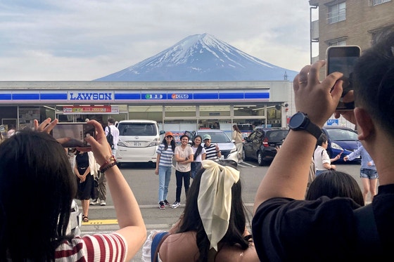 富士山の近くのあるコンビニで観光客たちが富士山を背景に写真を撮っている。優れた周辺景観のため観光客でにぎわうこのコンビニは、日本のオーバーツーリズムの象徴と見なされている。［写真 共同通信＝聯合ニュース］