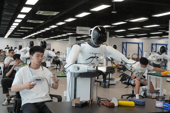 先月23日、浙江省紹興市上虞区の杭州湾エンボディドAI革新センターで、作業者がロボットを操縦しながらさまざまな作業環境に基づくデータを収集している。 新華社通信