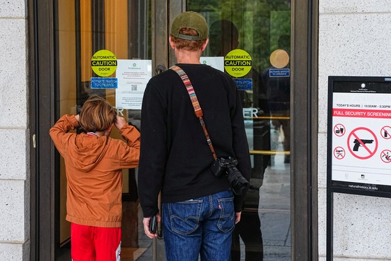 10月12日（現地時間）、米ワシントンD.C.のスミソニアン国立自然史博物館の前で、子どもが館内をのぞき込んでいる。博物館は米連邦政府のシャットダウン（一時的業務停止）が続くなか、暫定的に運営していた予算が尽き、閉館した。［ロイター＝聯合ニュース］
