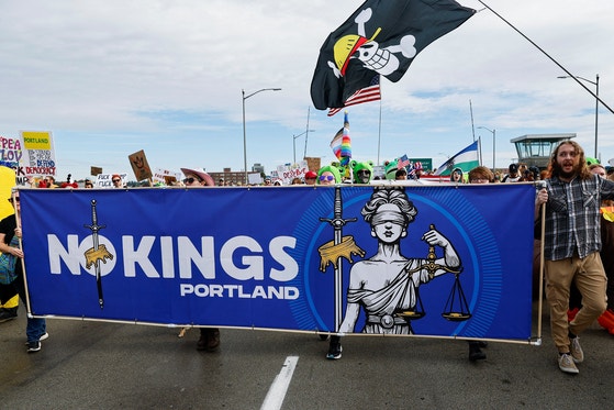2025年10月18日（現地時間）、米国オレゴン州ポートランドのマッコール公園とモリソン橋・ホーソン橋一帯に数万人の「ノーキングス（No Kings）」を叫ぶデモ隊が押し寄せ、参加者たちが横断幕を掲げている。［写真 聯合ニュース］