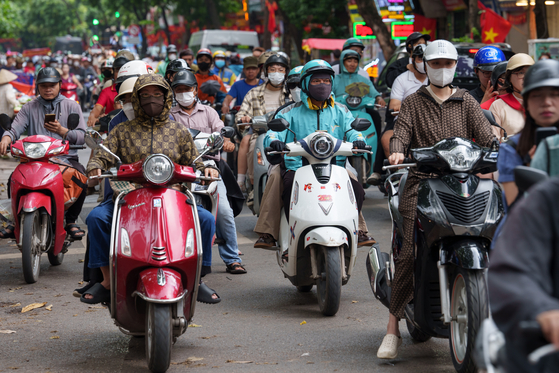 8月31日、ベトナムのハノイで市民がバイクに乗っている。［写真 AP＝聯合ニュース］
