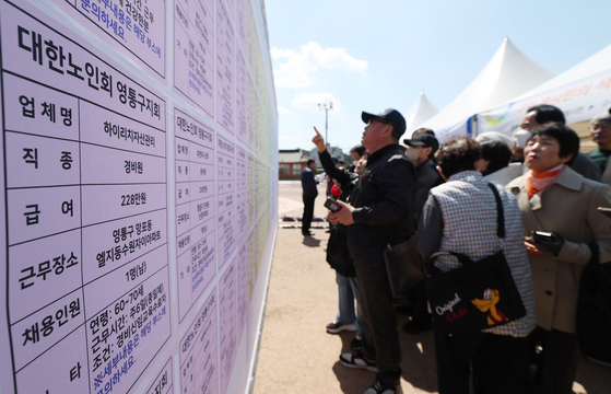 2025年第17回高齢者雇用採用フォーラムで60歳以上の高齢求職者が求人掲示板を見ている。［写真 ニュース1］