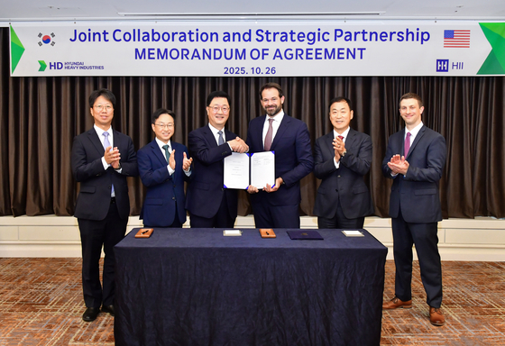  26日、APEC2025が開かれる予定である慶尚北道慶州のホテルでHD現代重工業の朱元浩特殊船事業部社長（左から3人目）とハンティントン・インガルスのエリック・チューニング戦略開発総括副社長ら両社関係者が「商船と軍艦建造協力に関する合意覚書」を締結した後記念撮影している。［写真 HD現代］