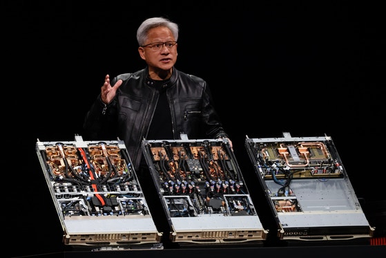 エヌビディアのジェンスン・フアン最高経営責任者（CEO）が5月に台湾のコンピューテクス2025で自社のGPU72個が搭載されたAIアクセラレータ「グレースブラックウェルNVL72」を見せている。［写真 EPA＝聯合ニュース］