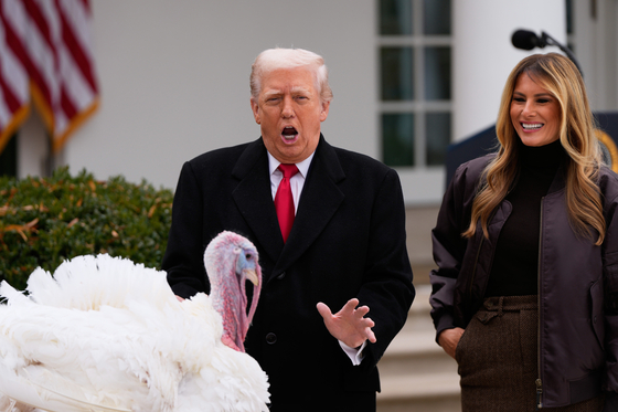 ドナルド・トランプ米国大統領（左）とメラニア夫人が、感謝祭を二日後に控えた25日（現地時間）、米国ワシントンD．C．のホワイトハウス・ローズガーデンで開かれた「七面鳥恩赦式」の行事で七面鳥を見ながら楽しそうな表情を浮かべている。AP＝聯合ニュース