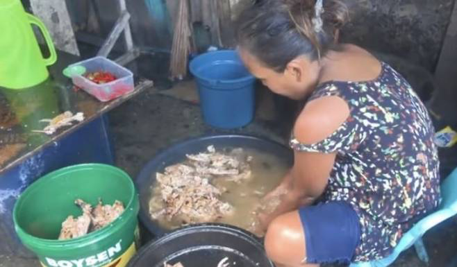 フィリピンの女性が捨てられた肉を洗っている。後にこれは販売商に売られる。 ［抖音（ドウイン）］