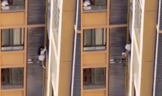   マンション10階の外側の狭い縁に立ち、助けを求める女性の様子。［中国SNS　キャプチャー］