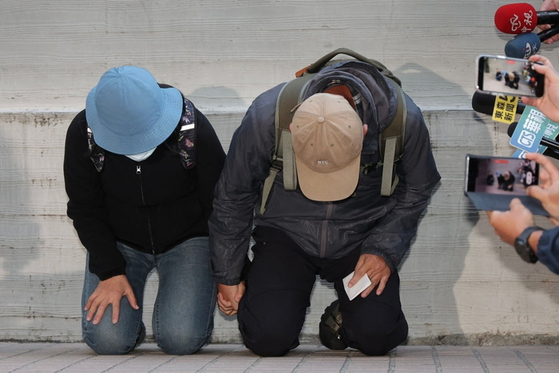 台湾・台北の地下鉄で起きた刃物殺傷事件の容疑者の両親が23日、台北市の法医解剖センターで取材陣の前にひざまずき、謝罪した。［AFP＝聯合ニュース］