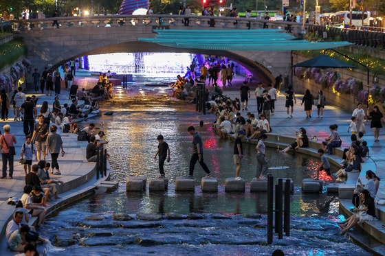 7月30日夕方、ソウルの清渓川を訪れた市民が足を水につけるなど散策を楽しみながら暑さをしのいでいる。［写真 ニュース1］