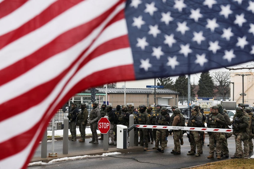 米ミネソタ州ミネアポリスの連邦庁舎前で、国土安全保障捜査局（HSI）と国境警備隊がデモ参加者の進入を阻止している。前方には、トランプ政権への抗議の意味として「逆さの星条旗」が掲げられている。［ロイター＝聯合ニュース］