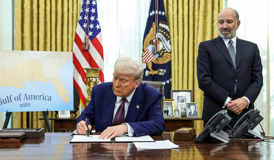  トランプ米大統領（左）が昨年、ラトニック商務長官の横で関税施行を指示する大統領令に署名している。［写真 ロイター＝聯合ニュース］