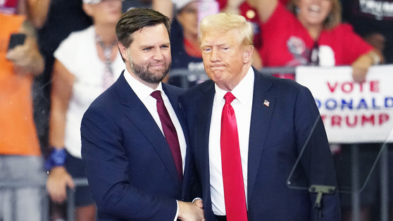 2024年8月、米アトランタのジョージア州立大学で行われた選挙集会で、ドナルド・トランプ当時大統領候補（右）とJ・D・バンス当時副大統領候補が握手を交わしている。AP＝聯合ニュース