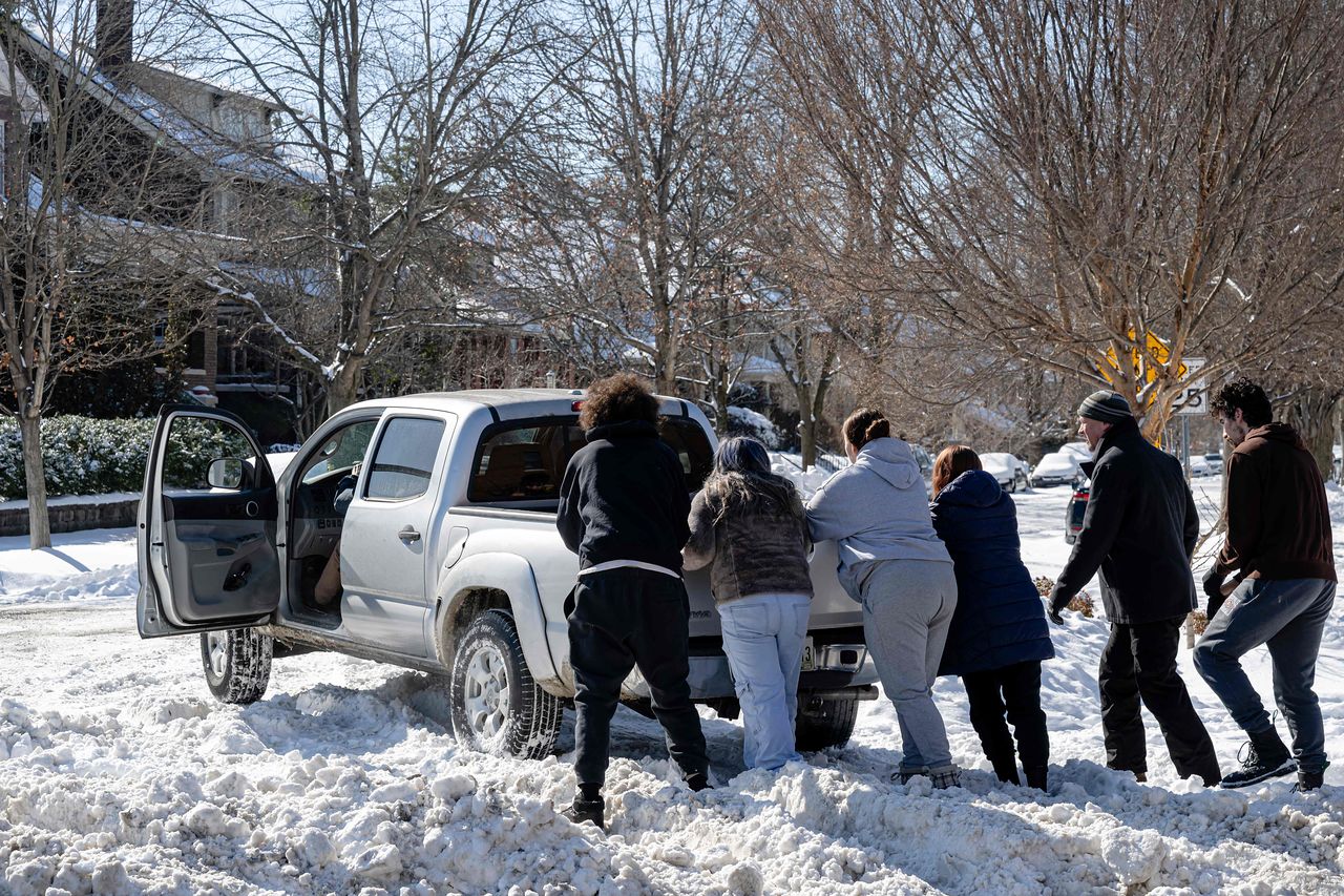   米国ケンタッキー州ルイビルで、雪で動けなくなったトラックを人々が押している。［AFP＝聯合ニュース］