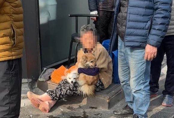   住宅火災現場で救助された後、飼い主の腕に抱かれている犬。［写真　論山消防署］