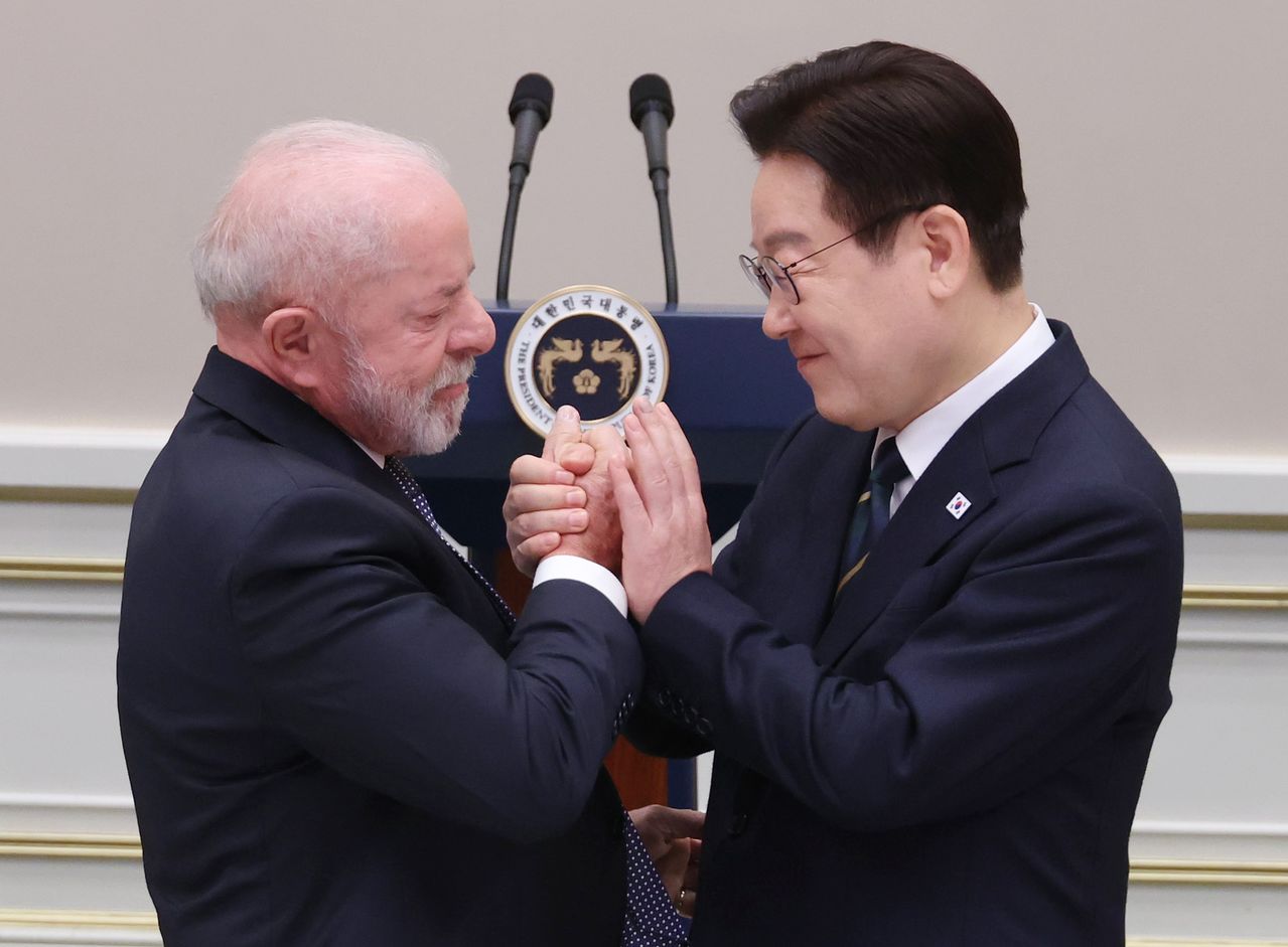 韓国の李在明（イ・ジェミョン）大統領が23日、青瓦台（チョンワデ、大統領府）で開かれたブラジルのルイス・イナシオ・ルーラ・ダ・シルバ大統領の国賓訪韓歓迎晩餐会で、答辞のために移動するルーラ大統領と手を握り合っている。［聯合ニュース］