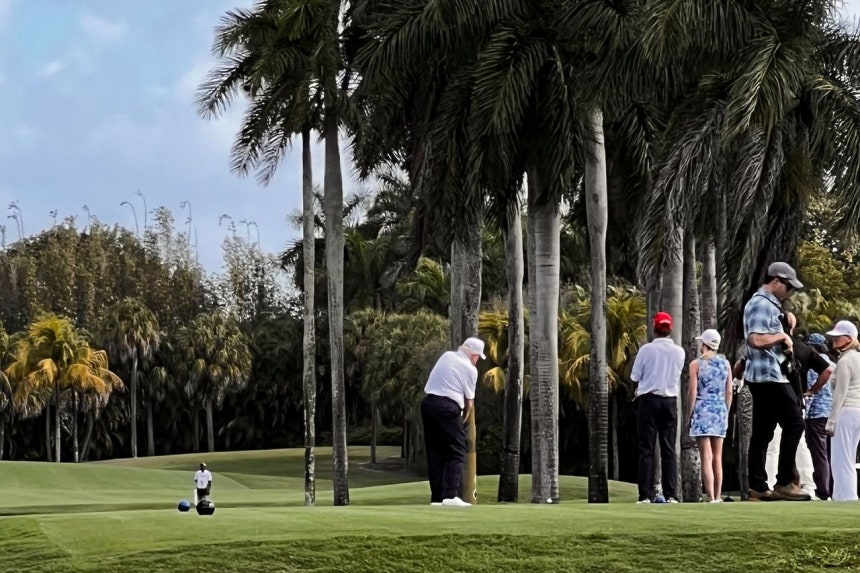 白い野球帽をかぶったトランプ米大統領（中央）が8日、フロリダ州のゴルフ場でゴルフをしている。銃を持つ警護スタッフも見える。［読者提供］