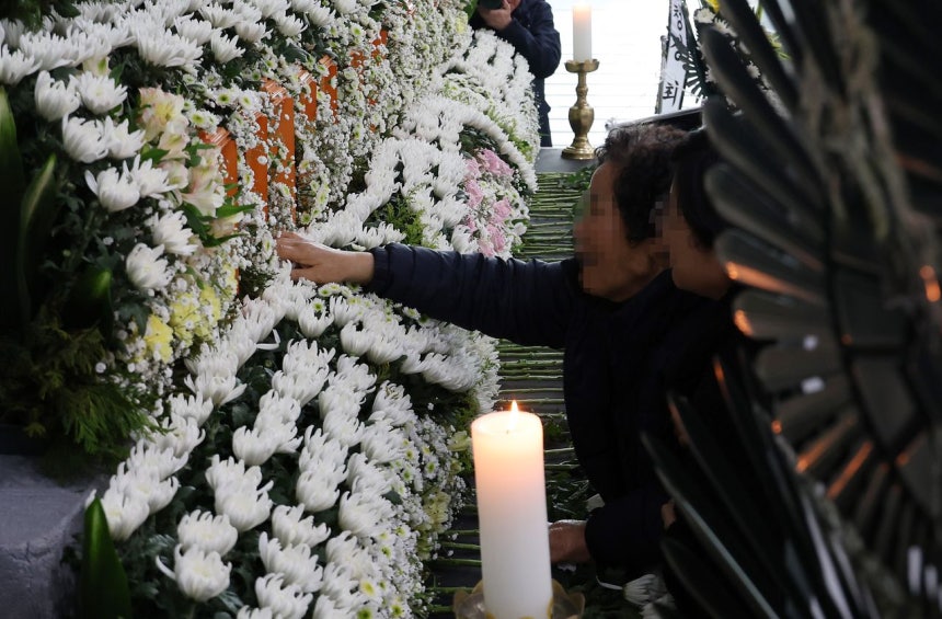 22日、大田（テジョン）市庁に設けられた安全工業の工場火災犠牲者を追悼する合同焼香所で、遺族が息子の名前が記された位牌に手を添えている。大田市は来月4日まで、市庁ロビーで合同焼香所を運営する。［聯合ニュース］