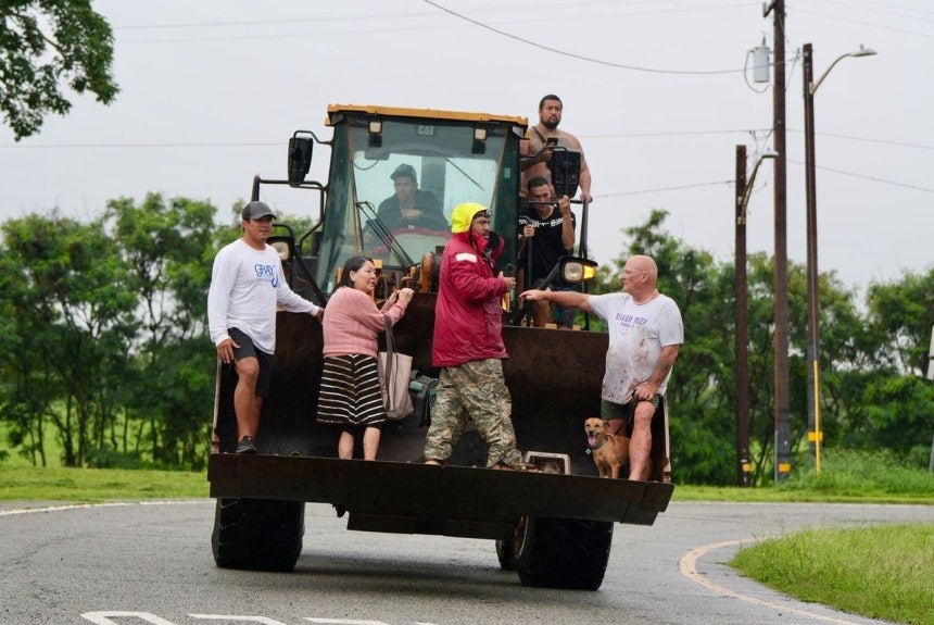 20日（現地時間）、米国ハワイ・オアフ島のハレイワで豪雨による洪水が発生し、住民たちがブルドーザーを利用して避難している。AP＝聯合ニュース 