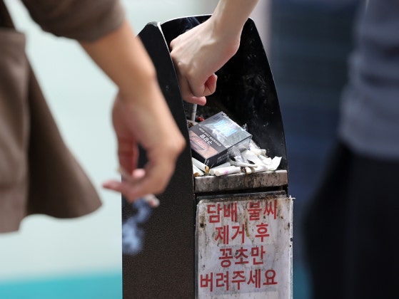ソウル市内の喫煙区域で市民が吸い殻を灰皿に捨てる姿。［写真 ニュース1］
