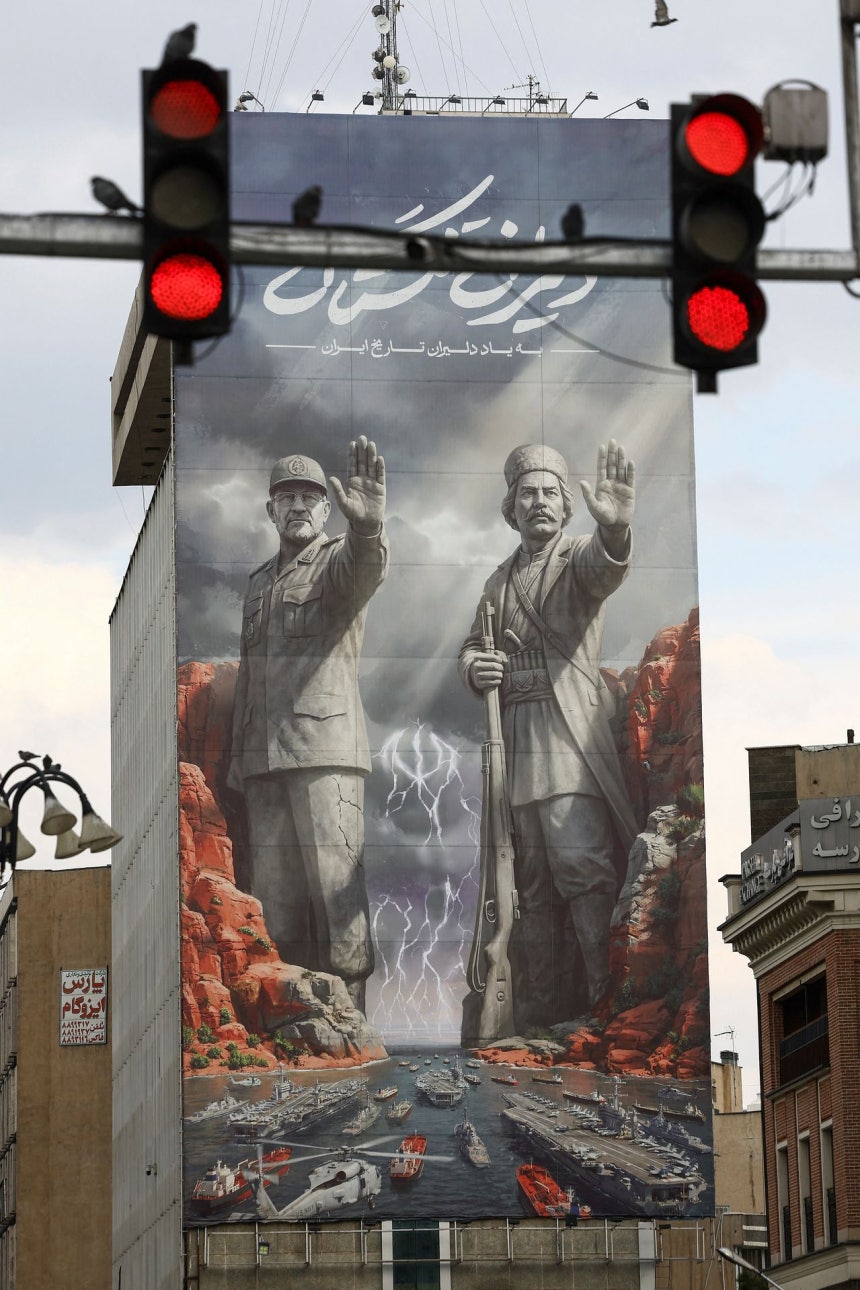 13日（現地時間）、イラン・テヘランに「イランの歴史的英雄を称えて」というフレーズとともに、2人の人物が米空母などを阻止するような絵が掲げられている。左は先月26日、ホルムズ海峡封鎖作戦中にイスラエルの空爆で死亡したアリレザ・タングシリ・イスラム革命防衛隊海軍司令官。右は1915年にイギリス軍と戦い死亡した民族的英雄ライス・アリ・デルバリ。ロイター＝聯合ニュース