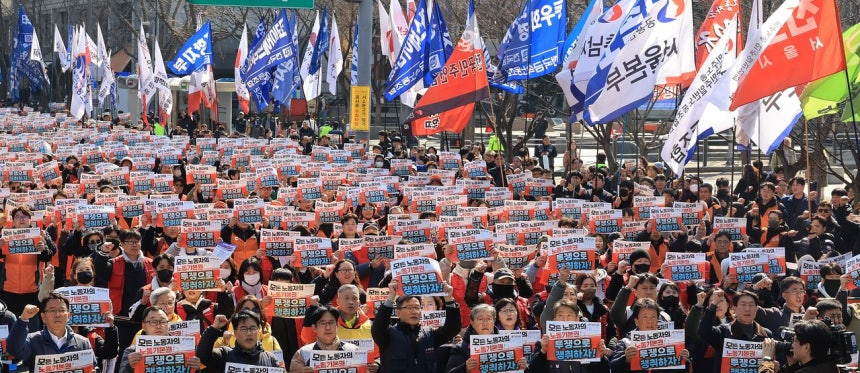 「黄色い封筒法」（改正労働組合法）施行初日の先月10日、ソウル世宗路（セジョンノ）で開かれた全国民主労働組合総連盟（民主労総）の闘争宣言大会で、組合員たちがプラカードを手にシュプレヒコールを上げている。聯合ニュース 