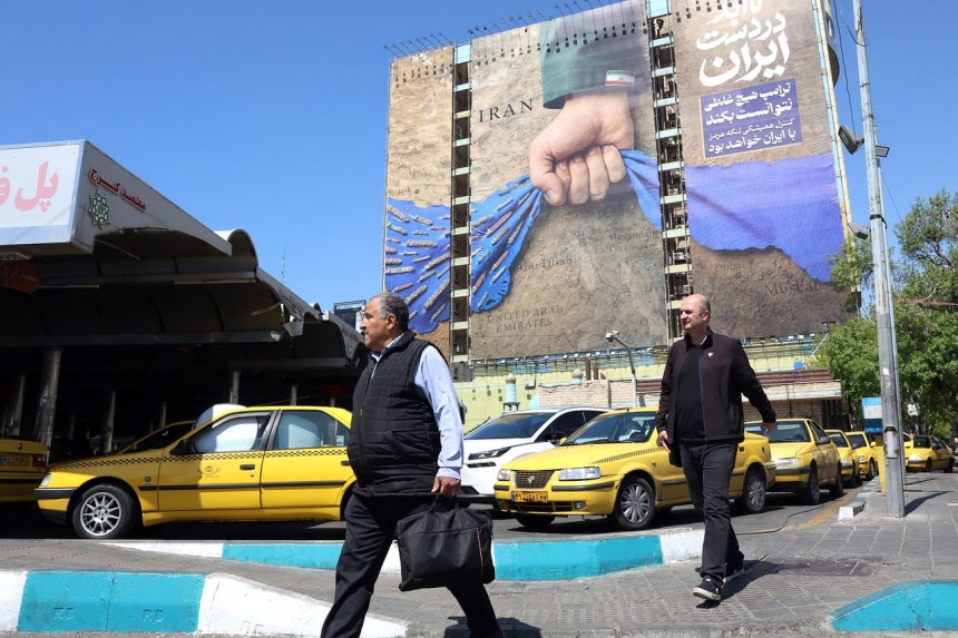 15日（現地時間）、イランの首都テヘランの風景。「ホルムズは永遠にイランの手に」と書かれた宣伝物の下を市民が歩いている。 ［EP＝連合］