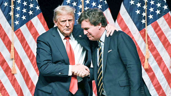 ドナルド・トランプ米国大統領（左）と保守系論客のタッカー・カールソン氏が2024年10月、大統領選当時のインタビューを終え、握手している。［AFP＝聯合ニュース］