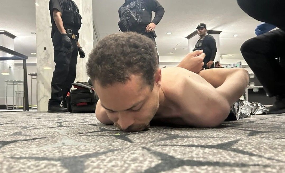   ホワイトハウス記者団夕食会の会場で発生した銃撃事件で制圧された容疑者。［写真 トゥルース・ソーシャル キャプチャー］