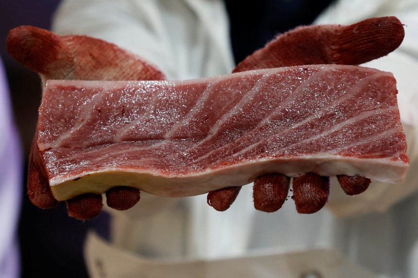   落札されたマグロの身の一部を持ち上げて見せる従業員。［ロイター＝聯合ニュース］