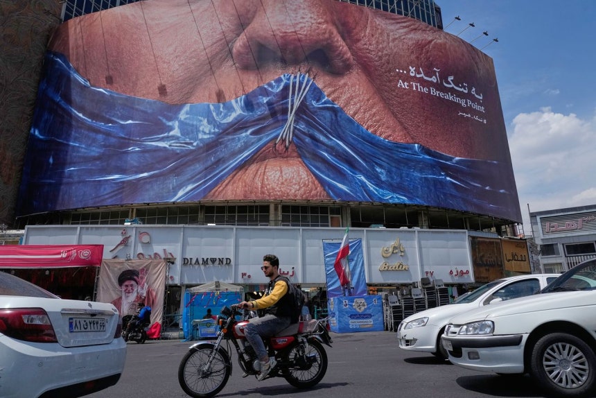 2日、イラン・テヘランのバリアスル広場にトランプ米大統領の口をホルムズ海峡を象徴する青い布でふさぎ、糸で縫い合わせたような姿の大型反米看板が設置された。［AP＝聯合ニュース］