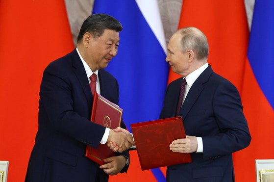 昨年5月8日、ロシア・モスクワの大統領府で中国の習近平国家主席とプーチン大統領が首脳会談直後に行われた共同声明署名式で握手している。 ［ロイター＝連合］