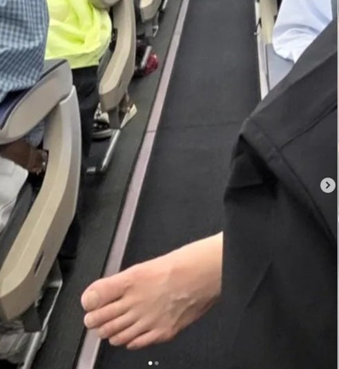  機内で騒動を起こした日本人乗客が、裸足のまま通路側に足を伸ばす様子。［SNS キャプチャー］
