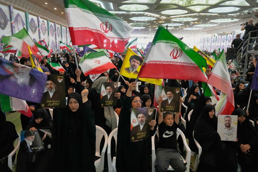 イラン政府の支持者らが24日（現地時間）、イラン・テヘランのイマーム・ホメイニ・モスクで行われた軍の記念式典でイランの国旗とイランの最高指導者モジタバ・ハメネイ氏の写真を掲げている。 ［AP＝聯合ニュース］