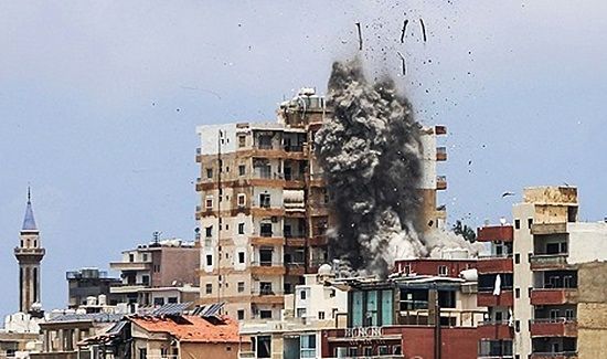 イスラエル軍の空爆後、煙とともにがれきが飛び散るレバノン南部ティールの建物。AFP＝聯合ニュース