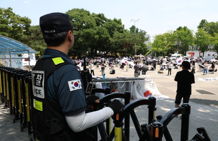 地方選挙での投票用紙不足を糾弾し再選挙を要求する蚕室開票所封鎖デモが続いている9日、オリンピック公園ハンドボール競技場出入口の前で警官が集会を見守っている。［写真 聯合ニュース］